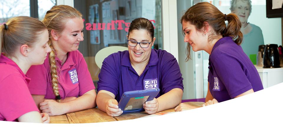 Verpleegkundestudenten en begeleiders van ZuidOostZorg kijken samen op een tablet