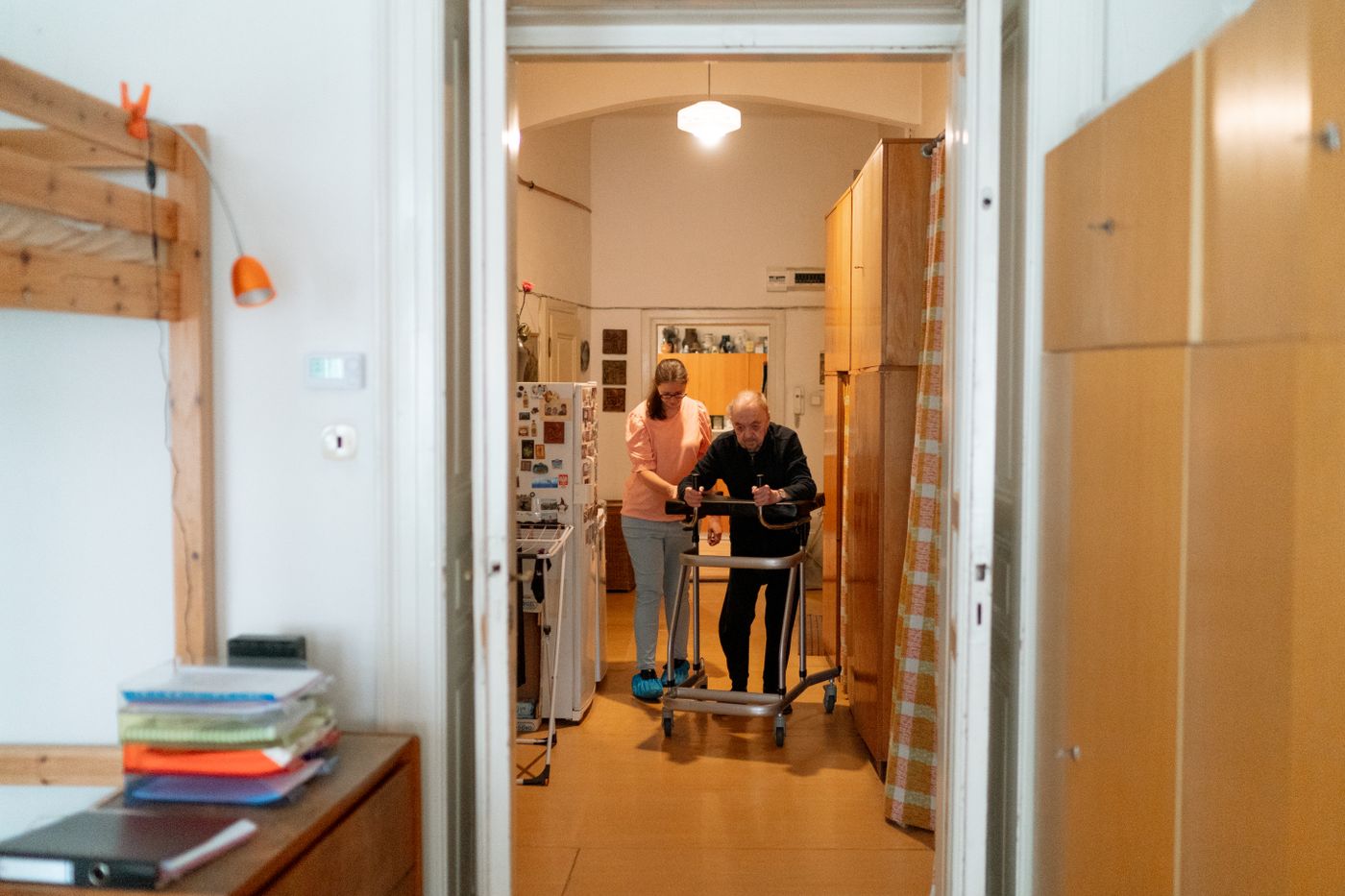 Een oudere man krijgt thuis ondersteuning bij het lopen met een rollator